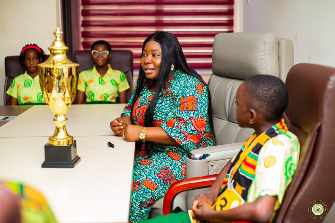 Eugene speaks with an official at the judges' table during a competition round, with the championship trophy resting on the table.