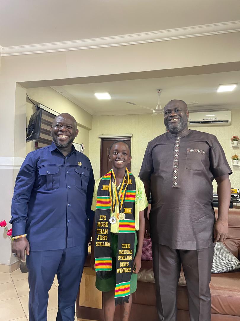 Eugene wearing his winner's medals and National Spelling Bee winner's sash, posing with two adults.